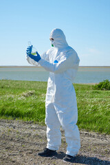 a man in a protective suit with a water sample in a flask. A scientist holds a flask of chemicals