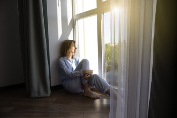 Woman sitting barefoot on the floor. Concept of underfloor heating and smart heating in the house.