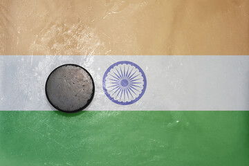 old hockey puck is on the ice with national flag of india .