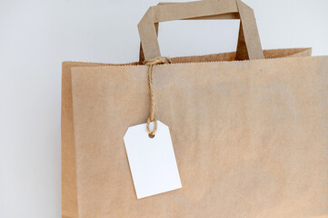 Part of a kraft package with a white tag on a rope with handles for delivery or gift
