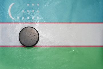 old hockey puck is on the ice with national flag of uzbekistan .