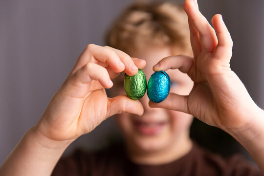 child with 2 bright Easter eggs in front of their face