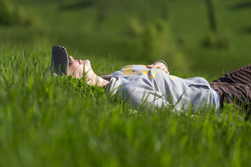 Young tourist woman taking a rest on green hill lying in the grass