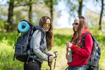 Two young hiker women standing on the trail in the forest