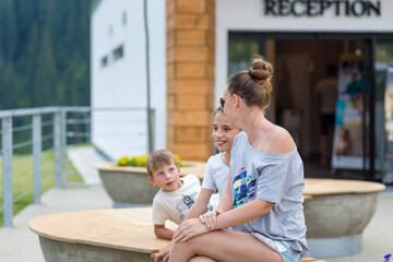 Young woman with her two children sitting outdoor at the lounge zone