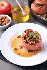 Tasty baked apple with nuts, honey and mint on gray table, closeup
