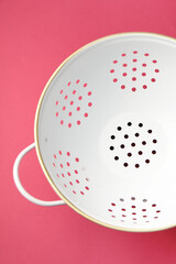 One clean empty colander on pink table, top view