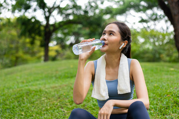 Asian young women drink water from a plastic bottle after exercises or sports. Asian woman running...