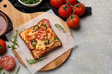 Tasty pizza toast, sauce, tomatoes and arugula on grey table, top view. Space for text