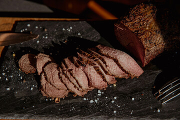 Steak cut into thin pieces and slices on a dark background