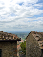 Naklejka premium stare kamienne kamienice w Cortonie, w tle widok na rozległą dolinę, Włochy