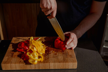 Man cutting red and yellow peppers on board
