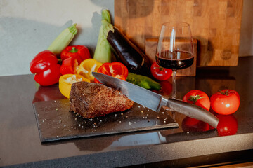 Steak and vegetables with a glass of red wine on the table