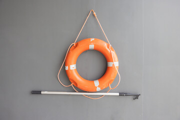 A life preserver is hanging on a wall next to a pole. lifebuoy hanging on wall.