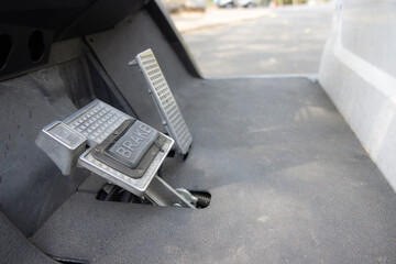 A brake pedal is shown in a close up of golf cart.