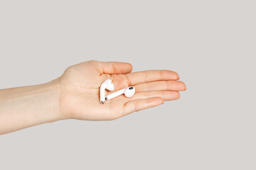 Closeup of woman hand showing white earphones for listening music, digital device. Indoor studio...