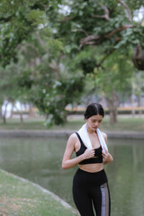 Beautiful Asian female runner doing morning exercise outdoors in city park. smile happily Exercise for good health