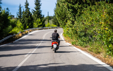 A man rides a scooter along the road.