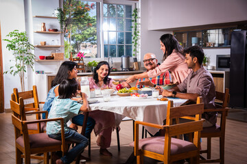 Indian family having lunch at home on dining table with grandparents, parents and kids