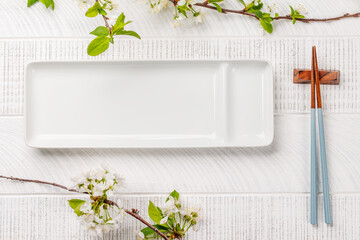 Table adorned with cherry blossom branch and chopsticks, epitomizing Japanese food culture