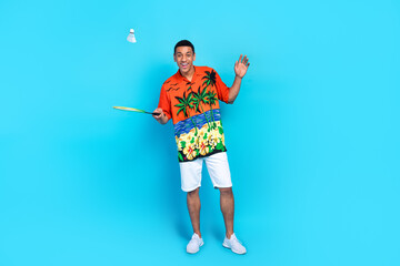 Full size portrait of nice young man play badminton summer holiday isolated on blue color background