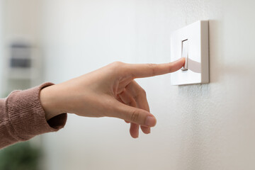 Save energy concept, Close-up finger of people turning off the electrical light switch on the wall...