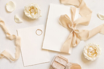 Cards tied with a beige silk ribbon on white table top view, copy space, wedding stationery mockup