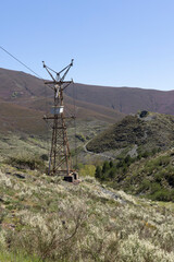 Abandoned industrial coal mining cart on cableway with rusty metal tower with cable on a bright...