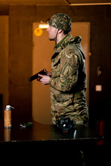 In a professional shooting range a military man in ammunition takes aim from a cleaned pistol
