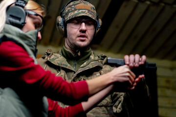 at a professional shooting range military man tells and shows a girl how to reload a pistol