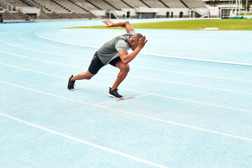 Fototapeta premium Black man, athlete and start position for running, cardio and fitness on outdoor track field. Male person, health and wellness outside in summer for exercise, training and workout at stadium