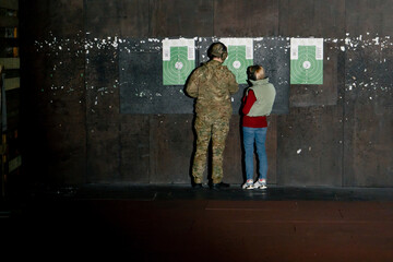 a professional shooting range military trainer and a girl check the target for hits