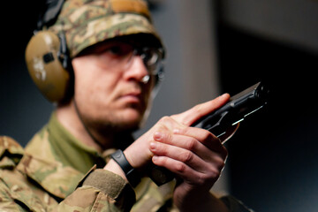 close-up at a professional shooting range a military trainer in ammunition takes aim with a pistol