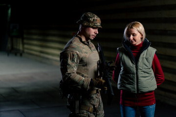 At a professional shooting range military trainer tells a girl how to properly handle NATO weapons