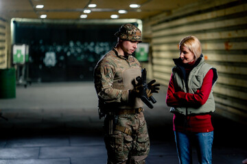 At a professional shooting range military trainer tells a girl how to properly handle NATO weapons