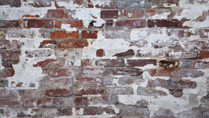 Horizontal background photo of an old vintage brick wall with crumbling plaster and mortar.