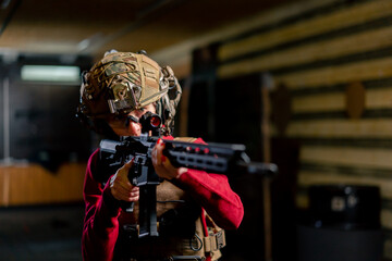 In a professional shooting range young girl in tactical ammunition is preparing to shoot