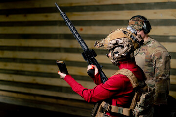 in a professional shooting range military man watches as a girl puts on a magazine for a rifle