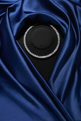 Diamond necklace on a black mannequin. Blue silk dress on a mannequin. Expensive luxury necklace. Top view.