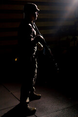 tactical strategy military man stands with a rifle in the dark contrast light back light silhouettes