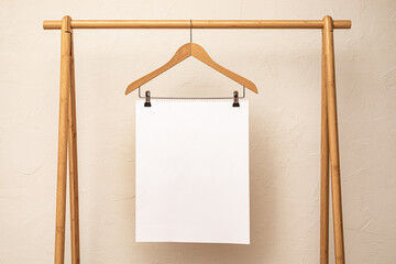 A piece of blank white paper for sale promo clipped to a wooden hanger on a simple rack