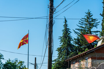 Macedonian Flags. Bridging Past, Present, and Future. Wooden post , electricity cables. Blue sky. 