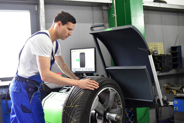 tyre change in a garage - assembler balancing a tyre on the machine