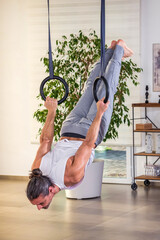 Flexible man exercising on suspended ring ropes