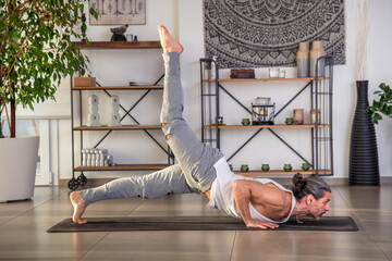 Man doing hatha yoga on mat in hall