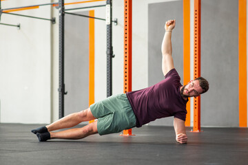 Man performing side plank calisthenics exercise in gym