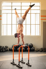 Strong man performing Straddle handstand on parallel bars calisthenic