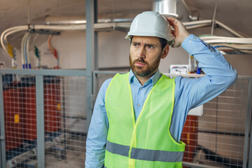 Handsome worker man wearing uniform and helmet on a plant looks clueless and confused expression....