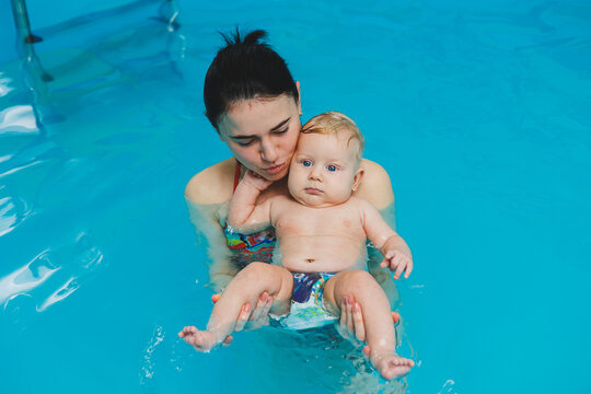 A baby learns to swim with a coach in the pool. Swimming pool for babies.