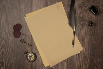 Vintage quill pen and empty old blank paper sheet with old accessories on wooden background from...